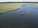 Aerial of two teenage boys kayaking through marshland on Bald Head Island, North Carolina.