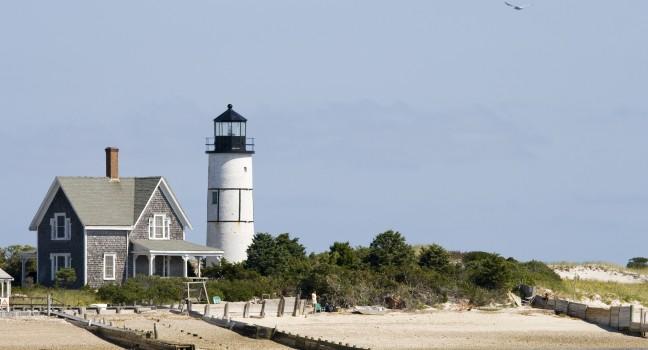 Wooden house and white lighthouse at Cape Cod near Portland.