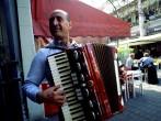 person; cityscape; urban; scene; Mercado del Puerto Montevideo, Uruguay, accordion, face, fingers, folklore, hand, instrument, man, music, musical, musician, people, performer, play, red, performance, outside, outdoors, town, city; Mercado del Puerto Monte