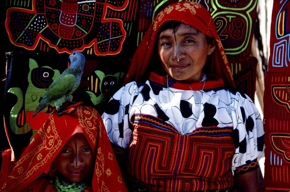 Amongst an archipelago of the San Blas Islands, a Cuna girl bedecked with a  gold nose ring peers though a cleft of fabric, an assortment of inverted appliques known as molas.