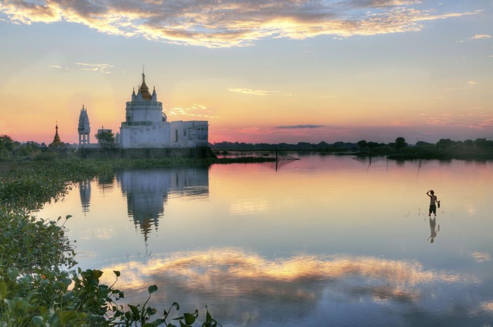 Buddhist temple at sunset reflecting in lake near U bein bridge at Amarapura ,Mandalay, Myanmar.