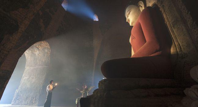 BAGAN, MYANMAR - FEBR. 14: Unidentified man is respecting Buddha statue inside the Pagoda on februari 14 2011 Bagan, Myanmar. 89% of the Burmese population is Buddhist.